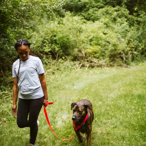 The Pet Spa & Resort Walk. Female Staff member and dog leash walking through a nature trail. 